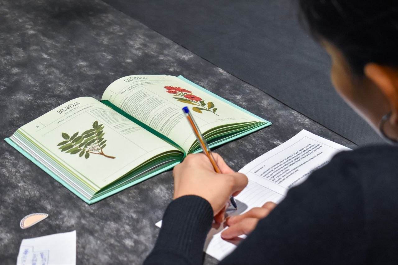 Persona tomando notas junto a un libro abierto