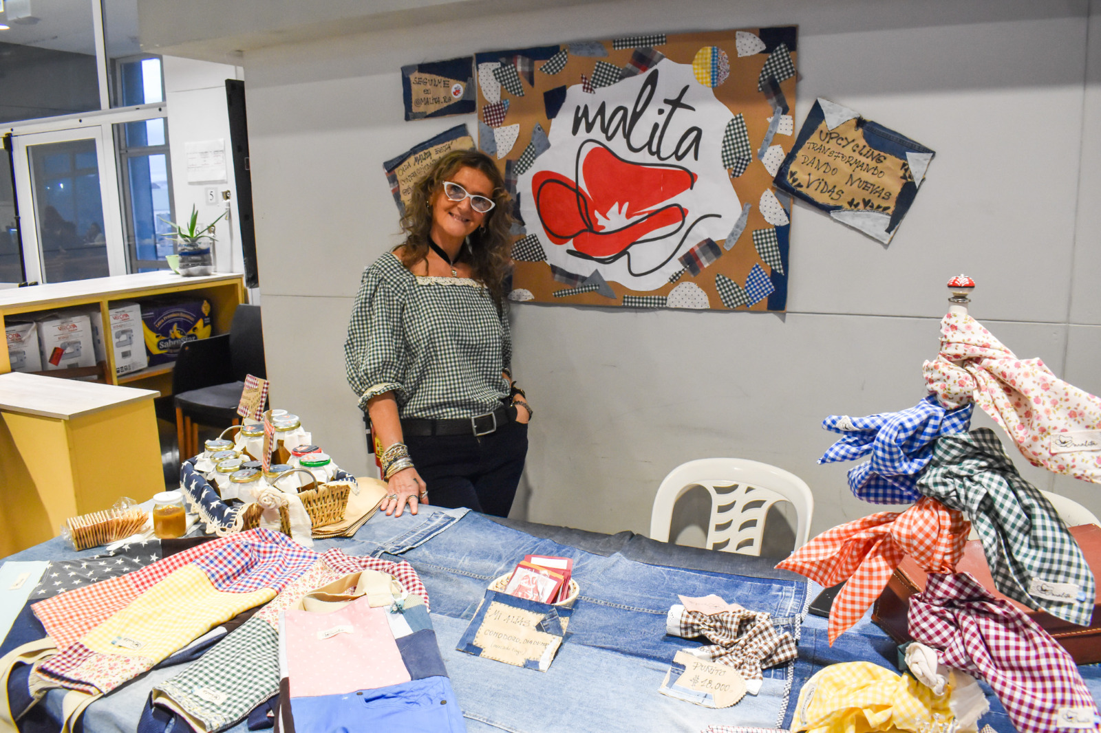 Expositora junto a una mesa con producciones textiles